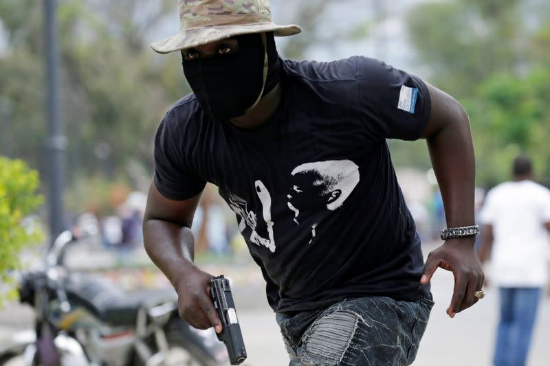 A protester carrying a gun runs during a shooting at a protest called by members of the police, in Port-au-Prince