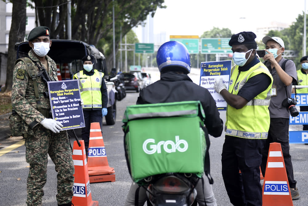 Soldiers and police officers conducting checks at a roadblock on day five of the movement control order (MCO) in Sri Hartamas March 22,2020. — Picture by Miera Zulyana