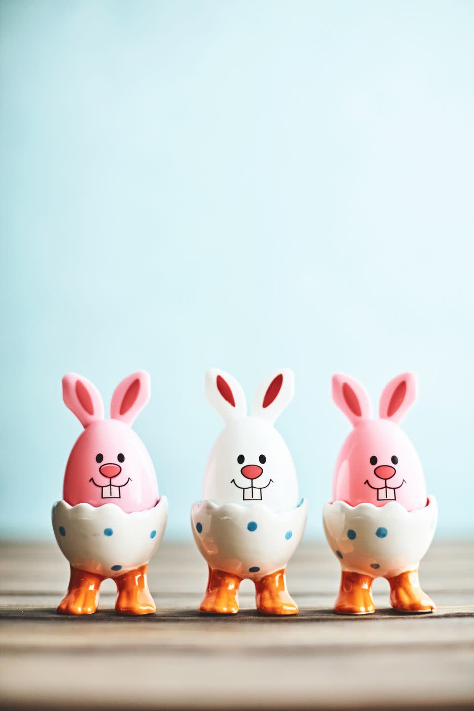 easter bunny trio in eggcups with blue background and rustic table top copy space for text