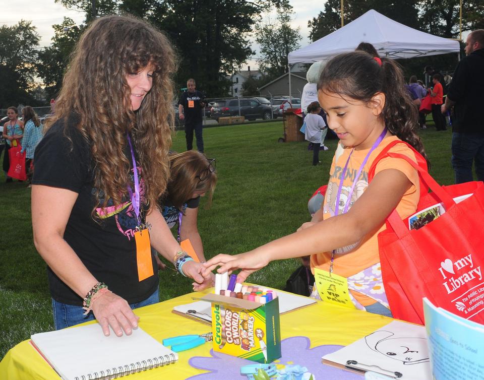 Shannara Harvey, illustrator of "Bernie the One-eyed Puppy," helps Gia Sabatine, 8, choose her colored markers during the Literacy Under the Lights event Saturday, Sept. 16, 2023, at Schaefer-Davies Stadium in Sebring. Harvey worked with children individually, giving tips on how to draw Bernie.