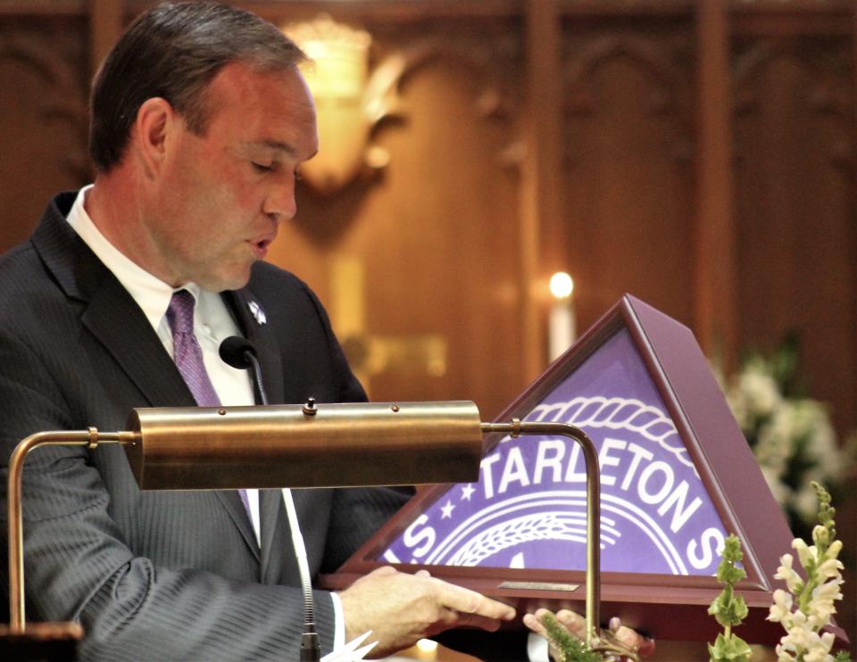James Hurley, president of Tarleton State University, presents a framed Tarleton flag to the Stenholm family to honor the late Charlie Stenholm. The former congressman was an adjunct professor at the university.