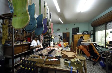 Argentine luthier Ezequiel Galasso (R) polishes a guitar neck at his workshop as his associate, musician and former skate pro Gianfranco De Gennaro, plays a guitar in Buenos Aires October 17, 2014. REUTERS/Marcos Brindicci