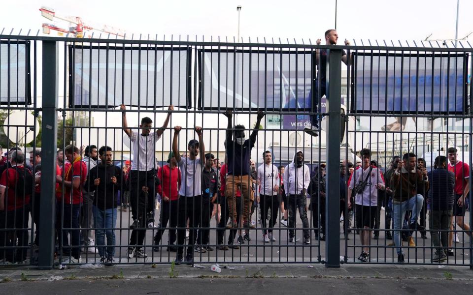 People try to climb gates outside the ground as the kick off is delayed during the UEFA Champions League Final at the Stade de France, - Adam Davy/PA