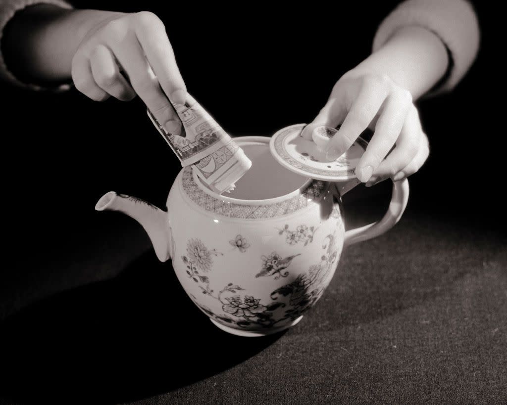 1930s Woman'S Hands Putting Cash Into Teapot Hiding Money Or Taking Money Out Of Teapot