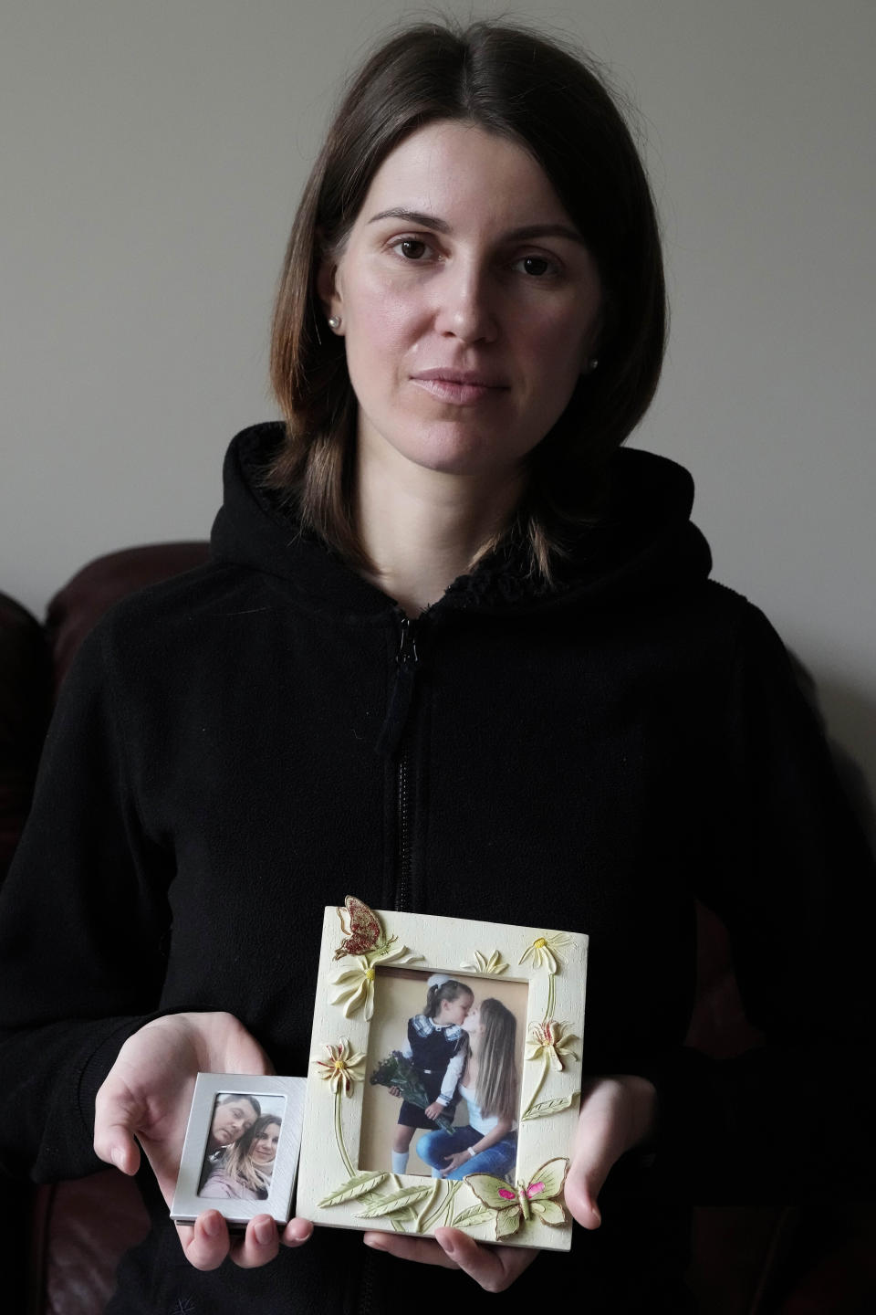 Viktoria Kovalenko shows pictures of herself with her husband and 12 year old daughter at her home in a village in Kent, Thursday, Feb. 9, 2023. Kovalenko chose to come to England not only because it offered her refuge from the war in Ukraine. It was also a chance for her to escape from her harrowing memories of losing her family in a shell attack. (AP Photo/Frank Augstein)