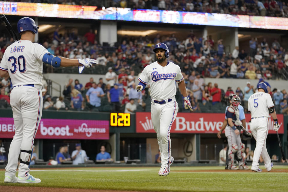 Texas Rangers' Nathaniel Lowe (30) and Marcus Semien, center, celebrate aftger Semien hit a lead-off solo home run in the first inning of a baseball game against the Texas Rangers in Arlington, Texas, Monday, Sept. 18, 2023. (AP Photo/Tony Gutierrez)