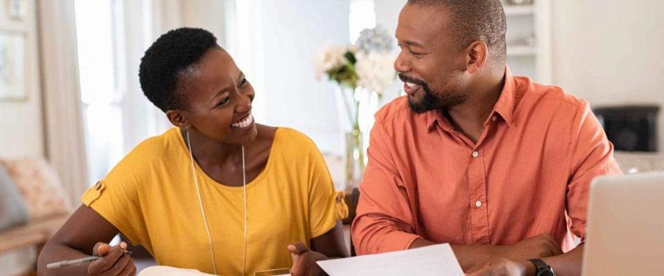 Mature Black couple sitting and managing expenses at home, finding cheaper homeowners insurance