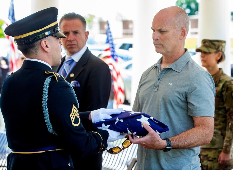 U.S. Army National Guard Pennsylvania Military Funeral Guard  Staff Sgt. Zuriel Nazario hands over the flag to Chris Wildman, of Linwood, a second cousin to WW II U.S. Army Pvt. Walter G. Wildman, of Bristol, Monday, May 23, 2022, at Washington Crossing National Cemetery.