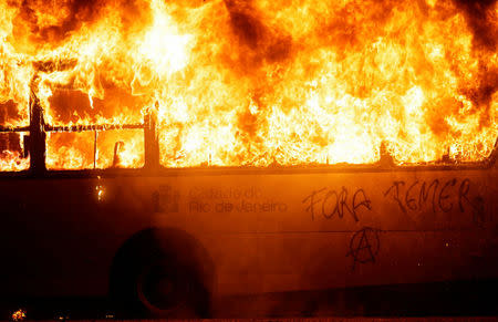 A bus burns during clashes between demonstrators and riot police in a protest against President Michel Temer's proposal reform of Brazil's social security system during general strike in Rio de Janeiro, Brazil, April 28, 2017. The writing reads, "Out Temer." REUTERS/Ricardo Moraes