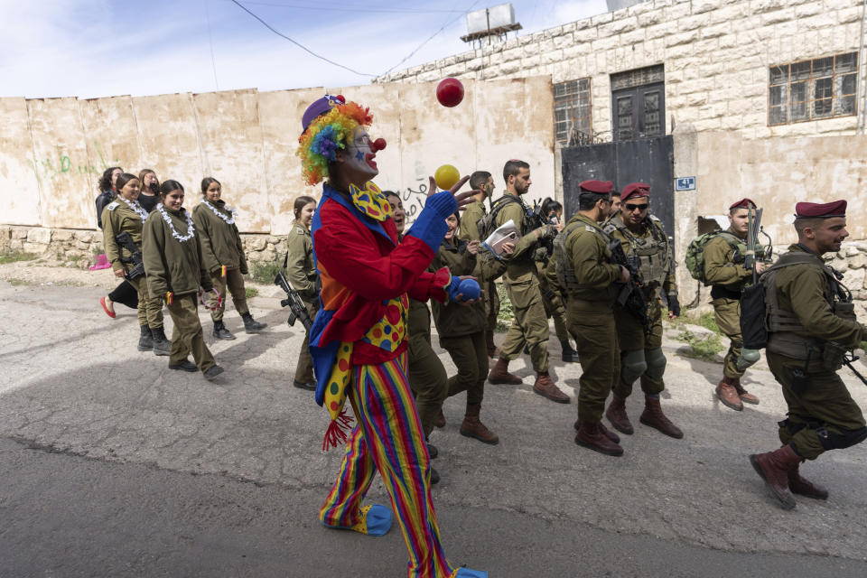 A Jewish settler dressed in costume celebrates the Jewish holiday of Purim as soldiers secure the march in the West Bank city of Hebron, Tuesday, March 7, 2023. Hebron is a flashpoint city where several hundred hard-line Israeli settlers live in heavily guarded enclaves amid some 200,000 Palestinians. The settlers each year hold a parade on Purim – a Jewish holiday marked by costumes and revelry that commemorates the Jews' salvation from genocide in ancient Persia, as recounted in the biblical Book of Esther. (AP Photo/Ohad Zwigenberg)