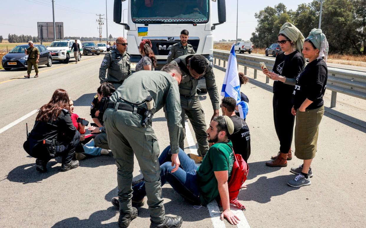 Israeli border guards and police speak with right-wing protesters blocking the road to Jordanian trucks carrying humanitarian aid supplies arriving on the Israeli side of the Kerem Shalom border crossing