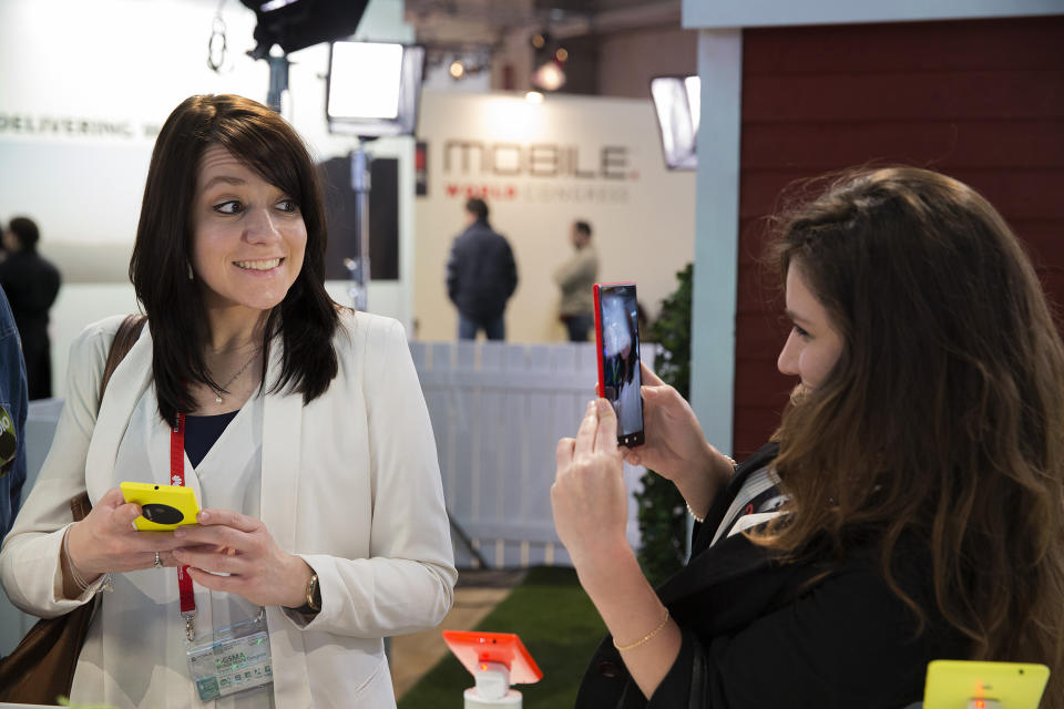 FILE - In this Tuesday, Feb. 25, 2014 file photo, a woman takes a picture with a Nokia Lumia 1520 phone as her friend smiles at the Mobile World Congress in Barcelona, Spain. The global wireless show that wraps in Barcelona on Thursday showed smartphone makers using software trickery to offset their camera weaknesses: inferior image sensors and lack of optical zoom lens. The companies are also making manipulating photos on the phone easier to learn than manually controlling DSLR cameras. (AP Photo/Marce Martinez, File)