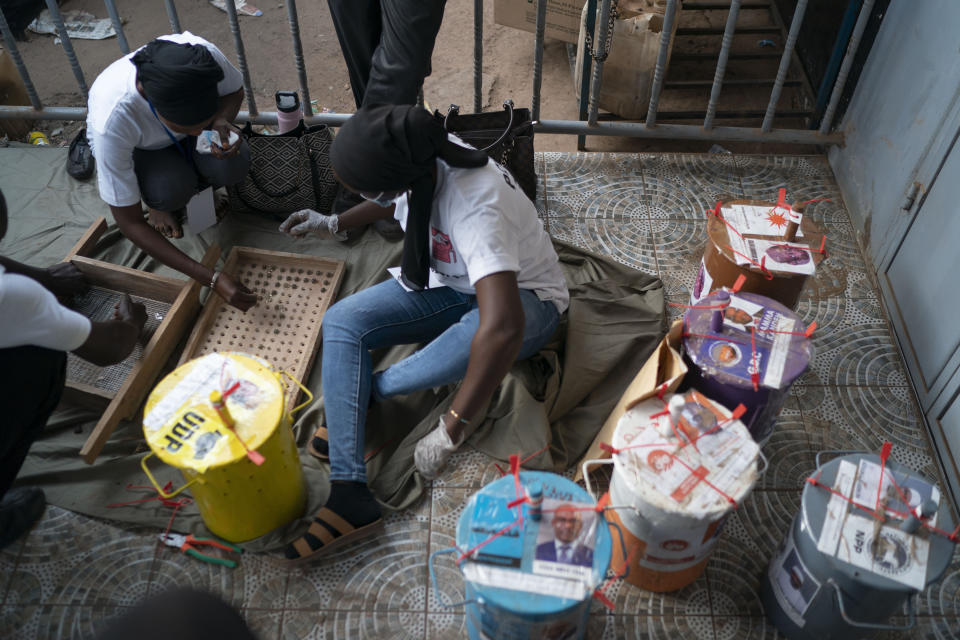 Electoral workers use a counting board to tally marbles from one polling station, during Gambia's presidential elections in Serrekunda, Gambia, Saturday, Dec. 4, 2021. Gambians vote in a historic election, one that for the first time will not have former dictator Yahya Jammeh appearing on the ballot. (AP Photo/Leo Correa)