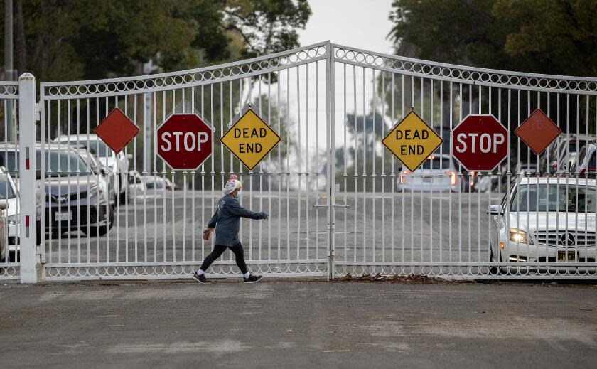 LOS ANGELES, CA-JANUARY 31,2024:A pedestrian walks along Gramercy Place in Los Angeles inside the "Pico Gates," that prevent people or cars from entering north of Pico Blvd. There is movement for and against opening the "Pico Gates," a set of gates that were installed around the Country Club Park neighborhood in an effort to protect them from society ills in the mid 1980's. (Mel Melcon / Los Angeles Times)