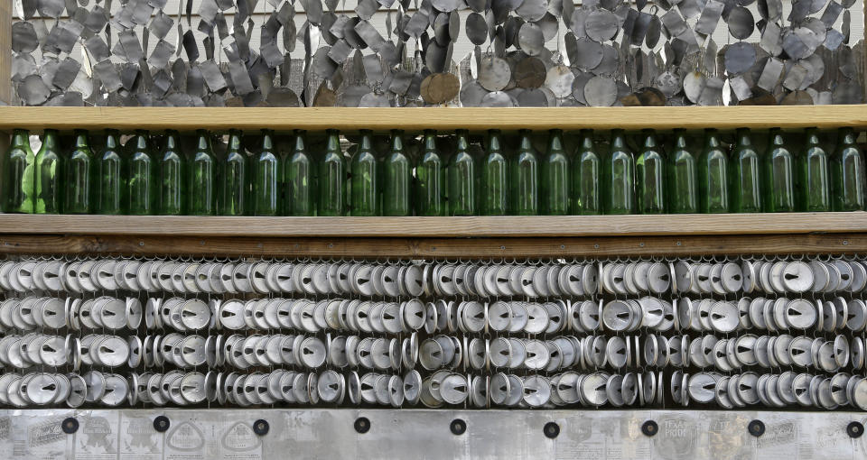 Beer bottles and different parts of beer cans line a fence in the yard of the beer can house, a Houston landmark, Wednesday, July 10, 2013. Former owner John Milkovisch covered the outside on the house with siding made of cut and flatten beer cans and garlands made from the lids. The Orange Show Center for Visionary Art, a local nonprofit that preserves art installations in the city, bought the property about 10 years ago, restored the house and it opened it to the public. (AP Photo/Pat Sullivan)