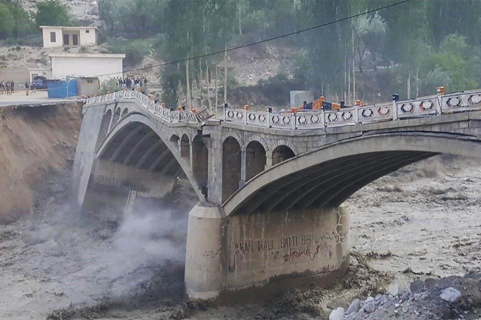 A photograph taken on May 7, 2022, shows a bridge partially collapsing due to flash floods sparked by a glacial lake outburst, in Hassanabad village, in Pakistan's northern Hunza district. / Credit: AFP via Getty