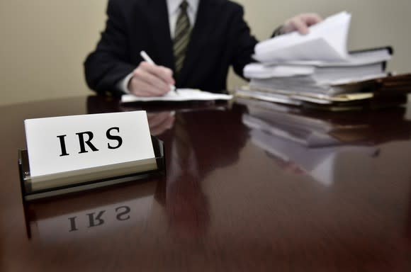 An IRS agent analyzing tax paperwork at his desk.