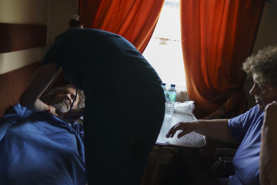 Viktor Holodeyev, 76, left, is tended to by a nurse while on an evacuation train with his wife, Tatiana, 72, as they depart from Pokrovsk, Donetsk region, eastern Ukraine, to travel west to a safer part of the country, Tuesday, Aug. 2, 2022. The image was part of a series of images by Associated Press photographers that was a finalist for the 2023 Pulitzer Prize for Feature Photography. (AP Photo/David Goldman)