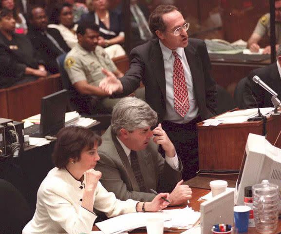 <p>POO/AFP via Getty </p> Alan Dershowitz (standing), while prosecutors remain seated. (L-R) prosecutor Marcia Clark and Scott Gordon.