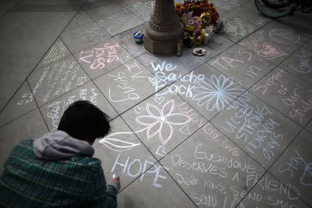 Students write chalk messages at a tribute for victims, at one of nine crime scenes after a series of drive-by shootings that left 7 people dead, in the Isla Vista neighborhood of Santa Barbara, California May 26, 2014. REUTERS/Lucy Nicholson