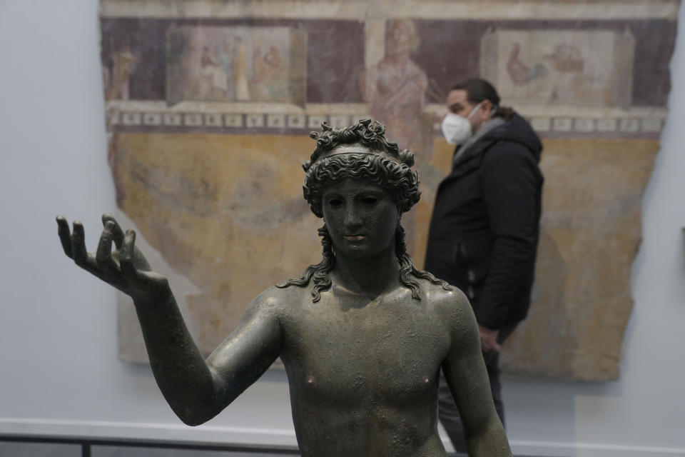 A man walks past the statue of Ephebos inside the museum Antiquarium in Pompeii, southern Italy, Monday, Jan. 25, 2021.Decades after suffering bombing and earthquake damage, Pompeii's museum is back in business, showing off exquisite finds from excavations of the ancient Roman city. Officials of the archaeological park of the ruins of the city destroyed in 79 A.D. by the eruption of Mount Vesuvius inaugurated the museum on Monday. (AP Photo/Gregorio Borgia)