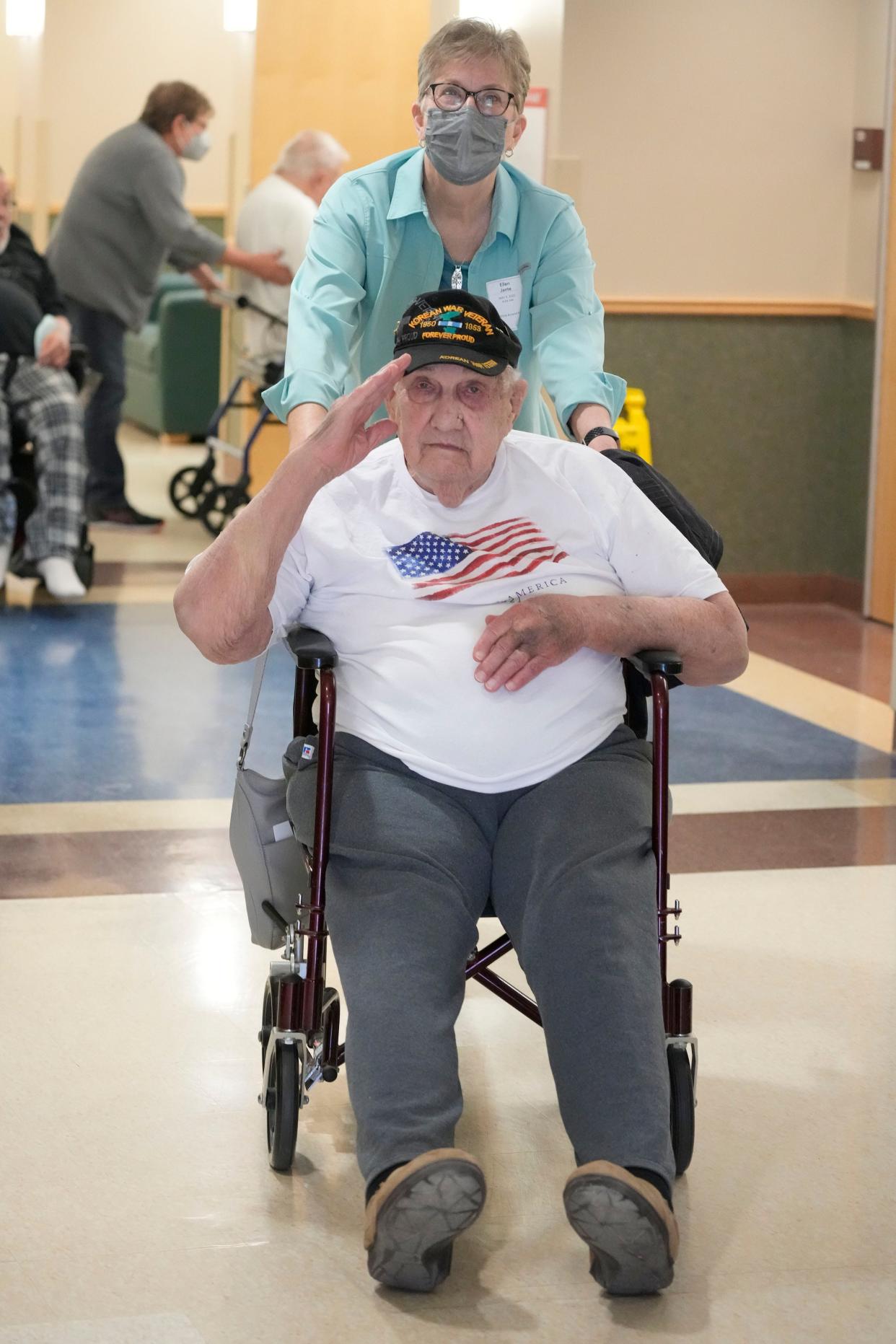 Veteran Gordon Voss, 91, salutes as volunteer Ellen Jante pushes him at the veterans home in Union Grove earlier this month. Voss said there are numerous problems with care, including not being able to get enough water, especially at night. "I am spitting cotton balls" by morning, he said.