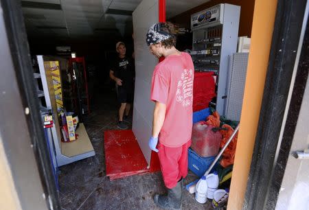 Jesse Strange (R) and Jeff Cutrer remove shelving from a convenience store at the South Point subdivision in Denham Springs, Louisiana, U.S., August 22, 2016. REUTERS/Jonathan Bachman