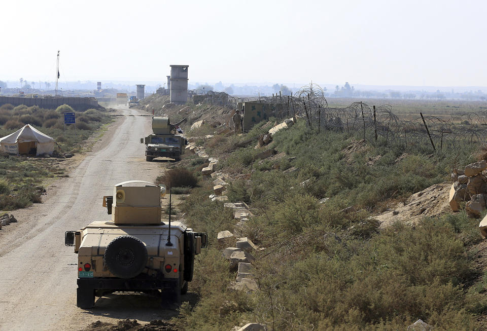 In this Tuesday, Nov. 13, 2018 photo, Iraqi soldiers patrol along the border between Syria and Iraq in Qaim, Anbar province, Iraq. More than a year after this Iraqi town was freed from the Islamic State group, booms from airstrikes still echo and columns of smoke are visible, rising beyond the earthen berms and concrete walls marking the border with Syria. On the other side, the fight is raging to capture one of the militant group’s last enclaves. (AP Photo/Hadi Mizban)