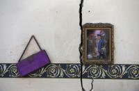 Un marco de fotos y un bolso cuelgan en la pared de una habitación en una casa destruida cerca del aeropuerto de Saná.