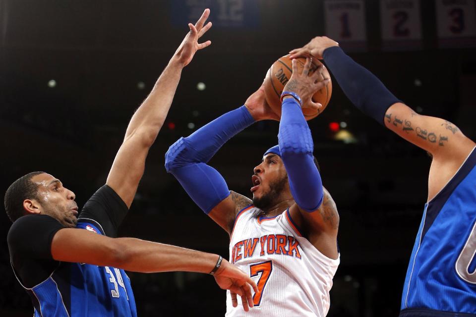 New York Knicks' Carmelo Anthony (7) shoots against Dallas Mavericks' Brandan Wright, left, and Shawn Marion during the first half of an NBA basketball game, Monday, Feb. 24, 2014, in New York. (AP Photo/Jason DeCrow)