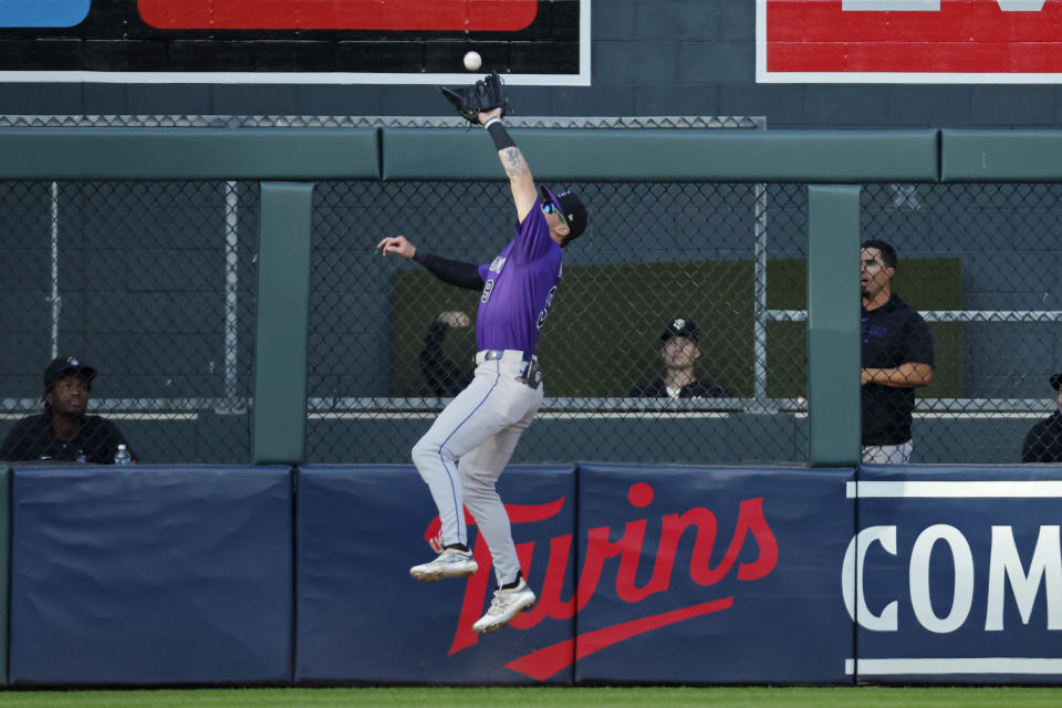 Colorado Rockies center fielder Brenton Doyle catches a fly ball at the fence by Minnesota Twins shortstop Carlos Correa in the fourth inning of a baseball game Tuesday, June 11, 2024, in Minneapolis. (AP Photo/Bruce Kluckhohn)