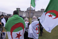 Demonstrators hold flags and protest against Algeria's President Abdelmadjid Tebboune outside of a conference taking place on Libya at the chancellery in Berlin, Germany, Sunday, Jan. 19, 2020. German Chancellor Angela Merkel hosts the one-day conference of world powers on Sunday seeking to curb foreign military interference, solidify a cease-fire and help relaunch a political process to stop the chaos in the North African nation. (AP Photo/Jens Meyer)