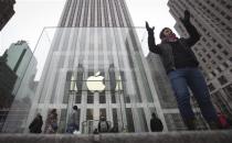 A man poses for a photo in front of the Apple store on 5th Avenue in New York, December 26, 2013. REUTERS/Carlo Allegri