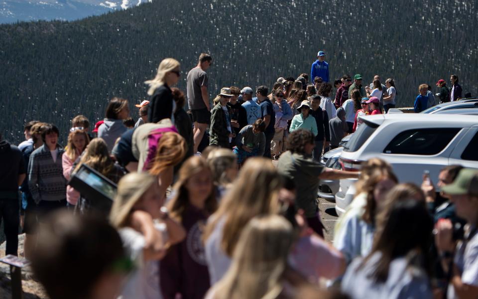 A crowd of people stand along an overlook in Rocky Mountain National Park on June 10, 2021.