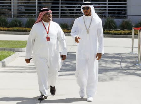 Formula One - Bahrain F1 Grand Prix - Sakhir, Bahrain - 03/04/16 - Mercedes F1 driver Lewis Hamilton of Britain (R) wearing a traditional Bahraini outfit "Thobe and Ghutra" arrives with Sheikh Abdulla bin Isa Al Khalifa, president of Bahrain Motor Federation. REUTERS/Hamad I Mohammed