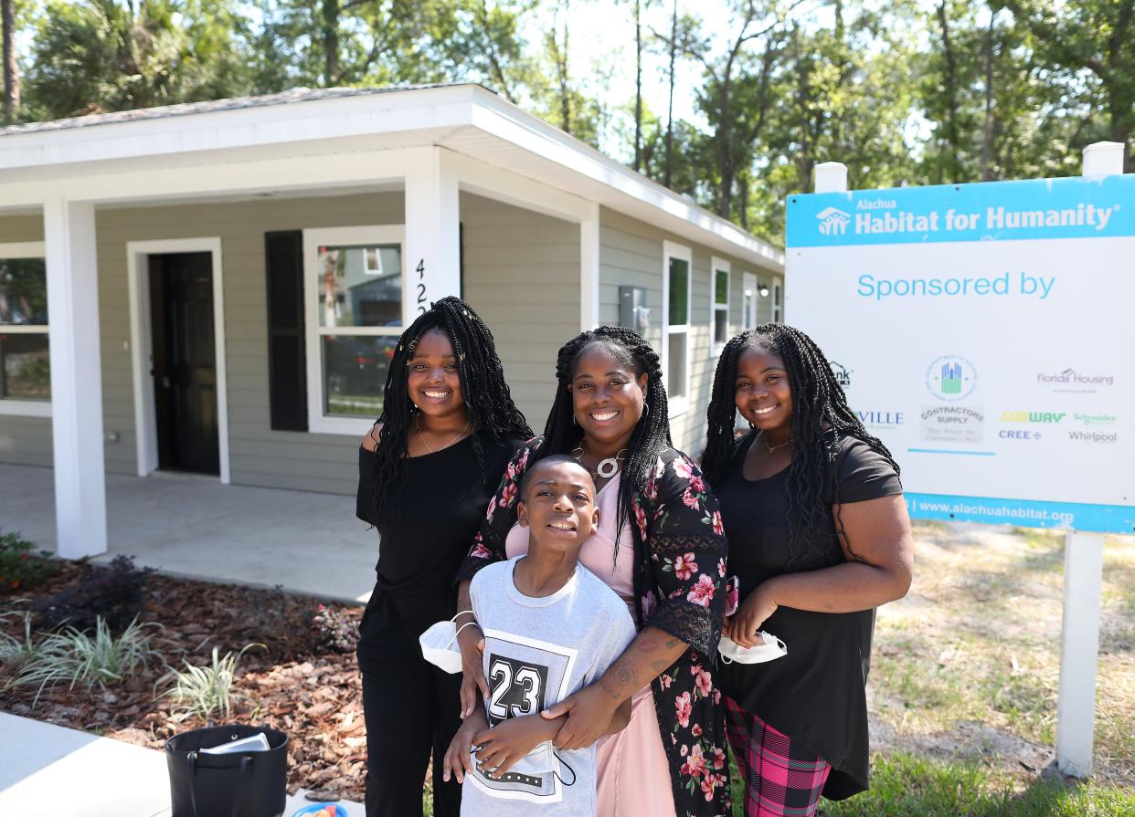Jasmie Cooper and her children, Takayla, Amya and Dayven, pose for a photo outside their new Habitat for Humanity home in Gainesville on May 18. A ceremony was held to dedicate the new home and give the keys to the home over to the Cooper family. [Brad McClenny/The Gainesville Sun]