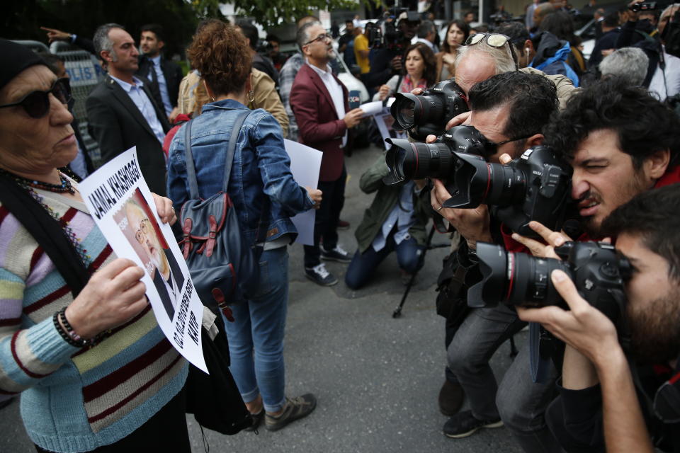 Photographers take pictures of an activist, a member of the Human Rights Association Istanbul branch, holding a poster with a photo of missing Saudi journalist Jamal Khashoggi, during a protest in his support, near the Saudi Arabia consulate in Istanbul, Tuesday, Oct. 9, 2018. Turkey said Tuesday it will search the Saudi Consulate in Istanbul as part of an investigation into the disappearance of a missing Saudi contributor to The Washington Post, a week after he vanished during a visit there. (AP Photo/Lefteris Pitarakis)