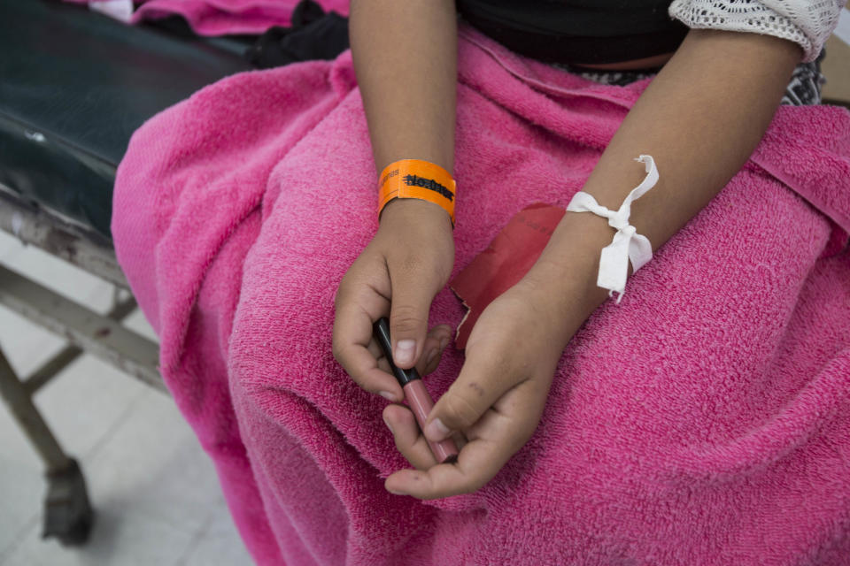 In this March 8, 2017 photo, a pink blanket covers a 16-year-old survivor of a fire that broke out at the Virgen de la Asuncion Safe Home, as she sits inside the emergency room at the Roosevelt Hospital in Guatemala City. The fire on March 8th that killed 40 girls at the shelter started when girls took a match to a foam mattress to protest the abuse they had suffered there. (AP Photo/Moises Castillo)