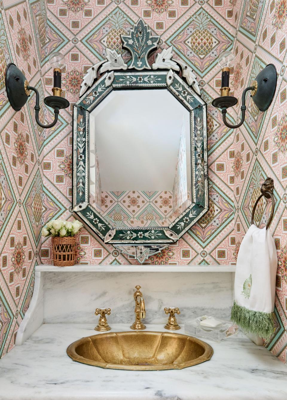 In the powder room, Roxy installed a pedestal sink, stone backsplash, and ledge before coming across the Gucci pineapple print wallpaper she felt was perfectly paired with a vintage Venetian mirror.