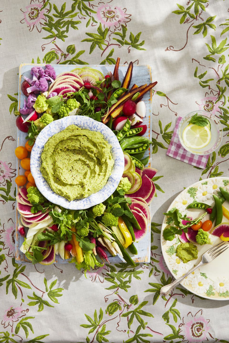 spring crudites board with white bean and pea dip in a bowl in the middle