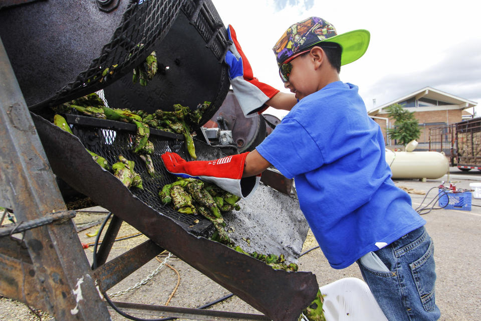 FILE - In this Aug. 9, 2017, file photo, Chris Duran Jr, 7 helps roast green chile with his family outside the Big Lots in Santa Fe, N.M. A hybrid version of a New Mexico chile plant has been selected to be grown in space as part of a NASA experiment, officials recently announced. (Gabriela Campos/Santa Fe New Mexican via AP, File)