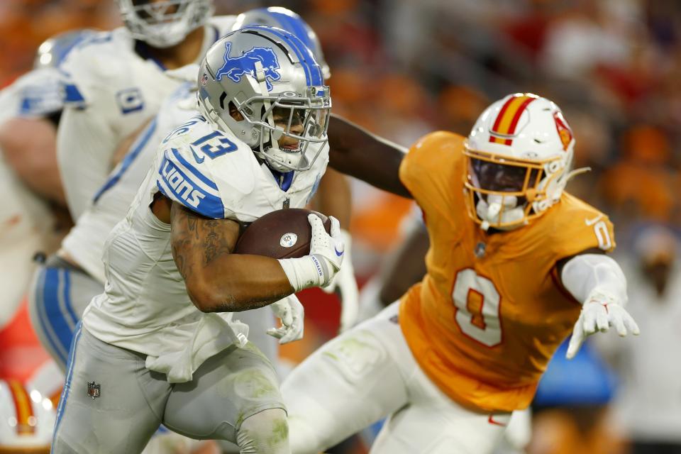 Craig Reynolds of the Detroit Lions runs past Yaya Diaby of the Tampa Bay Buccaneers during the fourth quarter at Raymond James Stadium on October 15, 2023, in Tampa, Florida.