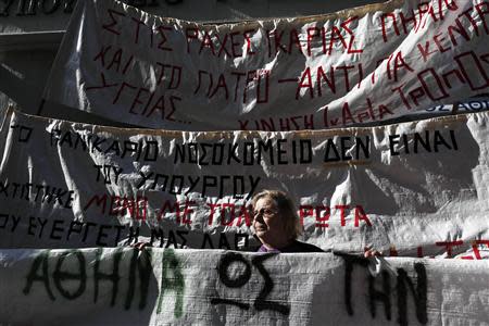 A woman stands between banners during a protest organised by unions from the state health sector against the government's plans for cutbacks in medical staff and hospitals in front of the Health ministry in Athens November 29, 2013. REUTERS/John Kolesidis