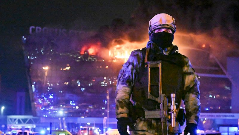 A Russian Rosguardia (National Guard) servicemen secures an area as a massive blaze burns over the Crocus City Hall on the western edge of Moscow, Russia, Friday, March 22, 2024. Several gunmen burst into a big concert hall in Moscow and fired automatic weapons at the crowd, injuring an unspecified number of people and setting a massive blaze in an apparent terror attack days after President Vladimir Putin cemented his grip on the country in a highly orchestrated electoral landslide.