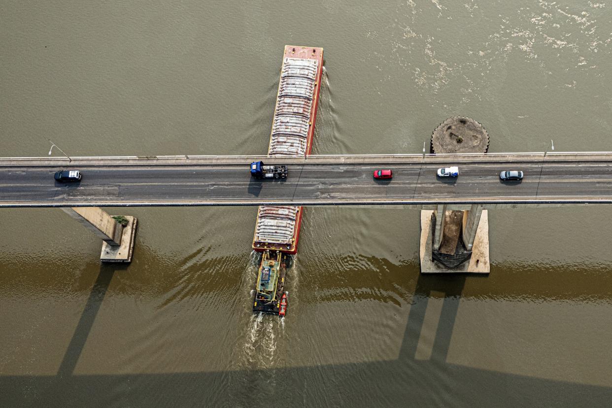 A tugboat pushes a barge under the Remanso bridge on the Paraguay River in Mariano R. Alonso, Paraguay, Monday, Sept. 9, 2024. Water levels have plunged to their lowest-ever level amid a drought, according to Paraguay's Meteorology and Hydrology Office. (AP Photo/Jorge Saenz)