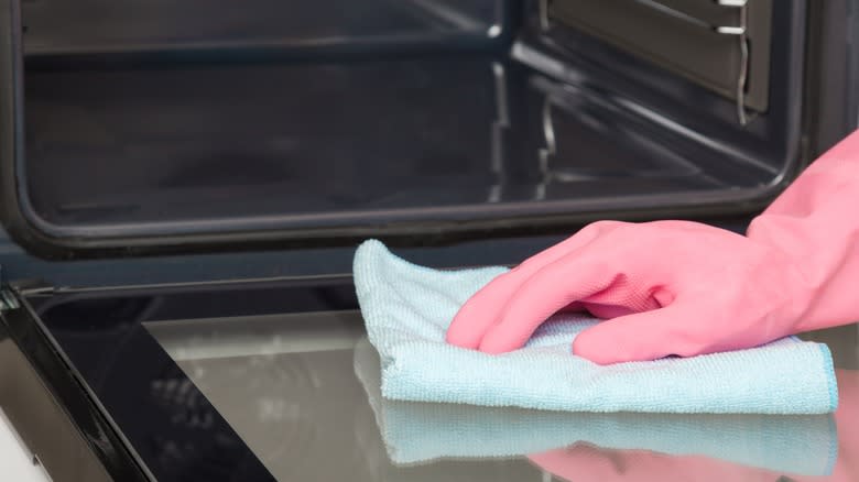 Pink glove wiping down oven door