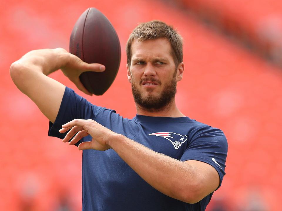 Tom Brady squints while throwing a football in 2014.