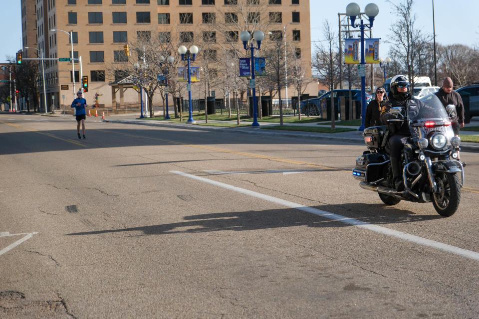 A motorcycle escort leads Jason Knapp down the final stretch of the 10K run Saturday in the 2023 Center City Mural Run in downtown Amarillo.
