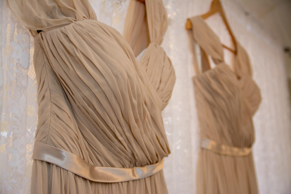 Two bridesmaids dresses next to each other on a curtain