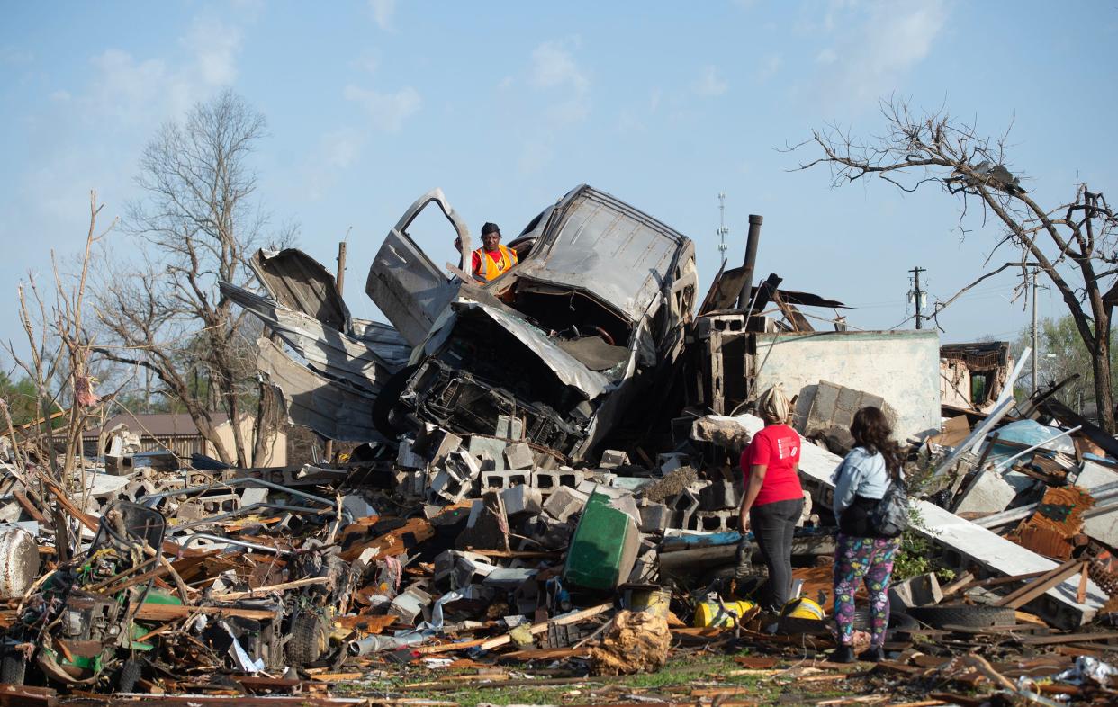 March 25, 2023/Clarion Ledger file photo — KeUntey Ousley of Rolling Fork, Miss., tries to salvage what he can from his mother's boyfriend's vehicle Saturday, March 25, 2023, after a tornado ripped through the Delta town Friday night. Below his mother LaShata Ousley, in red, and his girlfriend Mikita Davis wait. (Clarion Ledger/File photo)